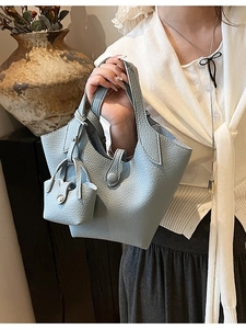 Light blue pebbled leather bucket bag with mini charm pouch shown on a model