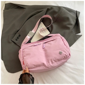 Detail of pink nylon crossbody bag with double purple zippers and adjustable strap