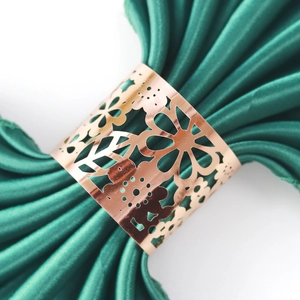 Hollow flower metal napkin ring in rose gold finish on deep green fabric decor