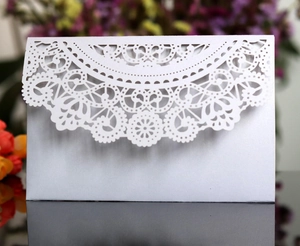 Macro detail of laser-cut lace pattern on pearlescent white wedding invitation envelope