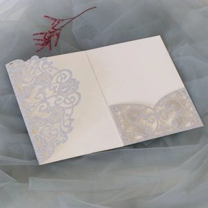 Close-up of laser-cut silver glitter wedding invitation with intricate hollow pattern