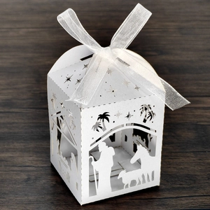 Detailed laser-cut nativity scene on a white paper gift box with a white ribbon bow