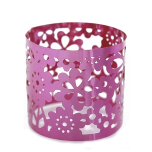 Detailed macro view of laser-cut floral pattern on pink metal hollow candle holder