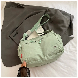 Close-up of mint green nylon crossbody bag with dual zippers and red brand tag
