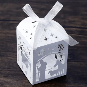 Detail of laser cut white paper gift box featuring nativity scene and organza ribbon bow
