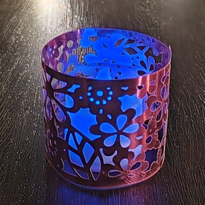 Close-up of laser-cut镂空 floral pattern on purple metal lampshade with blue LED light