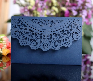 Macro detail of laser-cut navy blue wedding invitation with pearlescent lace texture