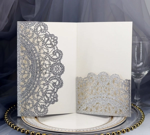 Macro shot of silver glitter laser-cut wedding invitation cover with intricate lace details