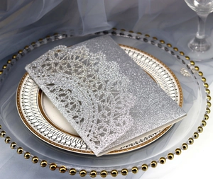 Macro detail of laser-cut silver glitter wedding invitation on elegant porcelain plates