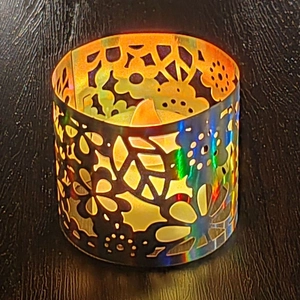 Cylindrical iridescent hollow paper lampshade with floral patterns and warm LED light