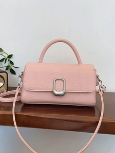 Fashionable pink faux woven handbag with silver buckle and crossbody strap on wood shelf