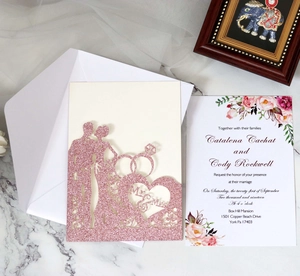 Macro detail of laser-cut glitter pink wedding invitation with Mr & Mrs silhouette design