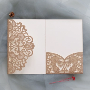Macro detail of laser-cut baroque champagne gold glitter invitation with elegant inner page