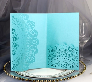 Detail of laser-cut teal blue wedding invitation cover with mandala lace patterns