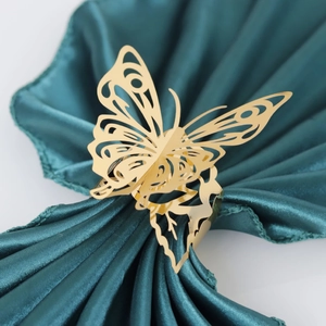 Close-up of golden hollow butterfly napkin ring on green satin fabric decor