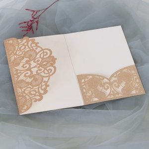 Detail of laser-cut gold wedding invitation with sparkling texture and baroque floral patterns