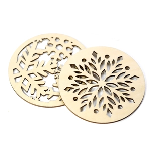 Detail of laser-cut snowflake patterns on natural wood coasters with a scorched edge finish