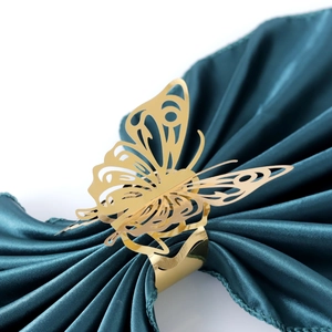 Macro detail of golden butterfly napkin ring with laser-cut hollow design on silk