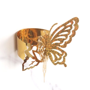 Macro detail of laser-cut golden butterfly napkin ring with sparkling glitter accents