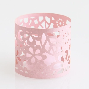 Macro shot of pink laser-cut decorative candle sleeve with floral lace and geometric patterns