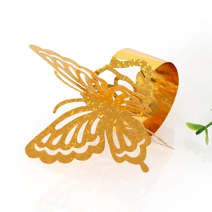 Detail of laser-cut hollow butterfly napkin ring with gold glitter finish for weddings