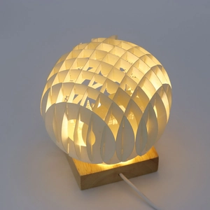 Detailed view of 3D hollow paper sculpture globe lamp on square wooden base with warm light