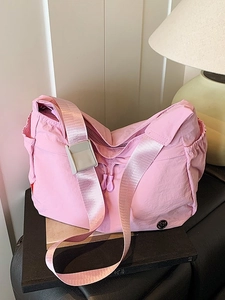 Pink nylon crossbody dumpling bag with wide shoulder strap and dual front zipper pockets