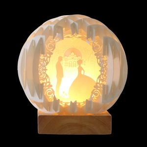 Detailed view of spherical paper-cut light with romantic couple silhouettes and wooden base