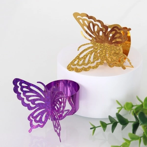 Macro detail of laser-cut butterfly napkin rings with gold and purple glitter finish