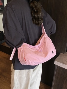 Pink nylon dumpling crossbody bag with adjustable wide strap and drawstring details