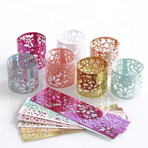 Close-up of laser-cut floral hollow napkin rings in various pearlescent metallic colors