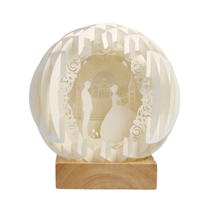 Detail of 3D paper-cut sphere light with wedding silhouettes and a natural wooden base