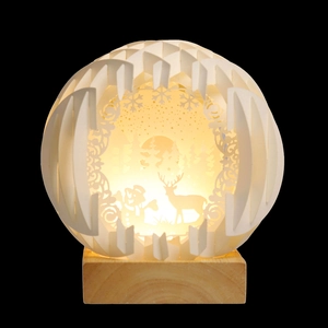 Macro detail of 3D laser-cut paper lantern with snowman, reindeer and warm LED glow