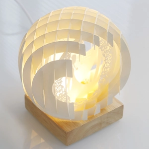 Detailed laser-cut paper carving ball lamp with warm LED light and wooden base