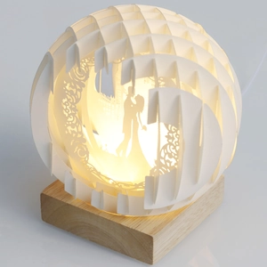 Detailed close-up of 3D paper cut light sphere with couple silhouette and wood base