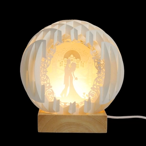 Detail of 3D paper-cut sphere light featuring a romantic couple and solid wood base
