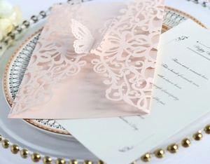 Close-up of laser-cut pink wedding invitation with butterfly design and white inner card