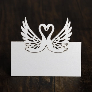 Close-up of laser-cut swan heart place card with pearl finish on wood background