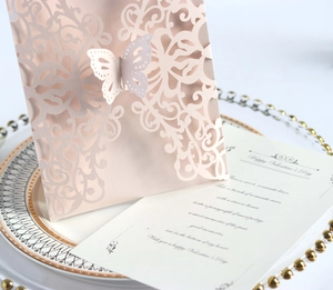 Detail of pink laser-cut invitation featuring a 3D butterfly and elegant paper pattern