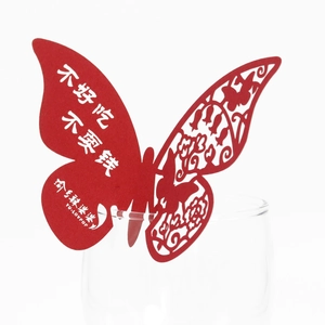 Detail showing red laser-cut butterfly place card with hollow pattern on a glass rim