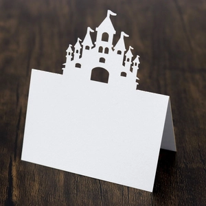 Macro shot of laser-cut white castle silhouette place card on a dark wood background