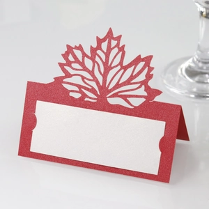 Macro detail of red laser-cut maple leaf place card with elegant glitter finish and name space