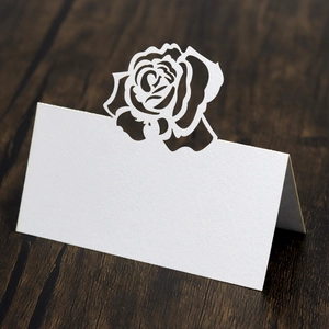 Macro view of white pearlescent laser-cut place card with rose hollow design on wood