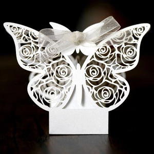 Detail of laser-cut white butterfly candy box with rose pattern and organza ribbon