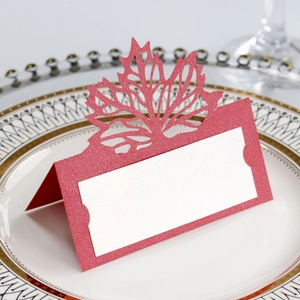 Close-up of laser-cut red maple leaf place card on a white decorative plate
