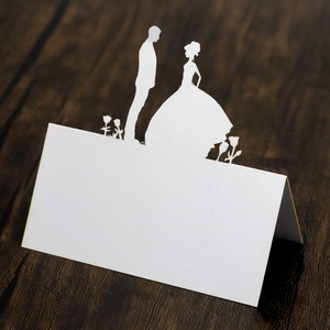 Close-up of laser cut wedding place card with bride and groom silhouette in white paper