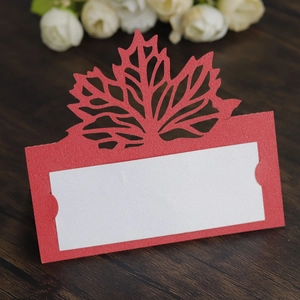 Close-up of laser-cut red maple leaf place card with pearlescent insert on wooden surface