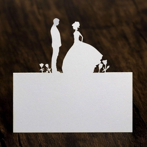 Laser-cut white wedding place card featuring elegant bride and groom silhouette on wood