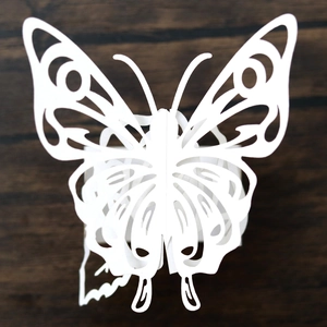 Detailed view of laser-cut white butterfly napkin ring with 3D wings on wood