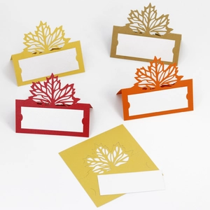 Macro detail of laser-cut maple leaf place cards in autumn colors for Thanksgiving events